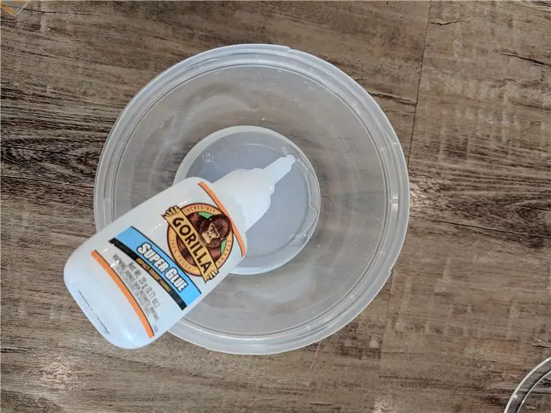 Superlijm de kleine plastic container op de grote